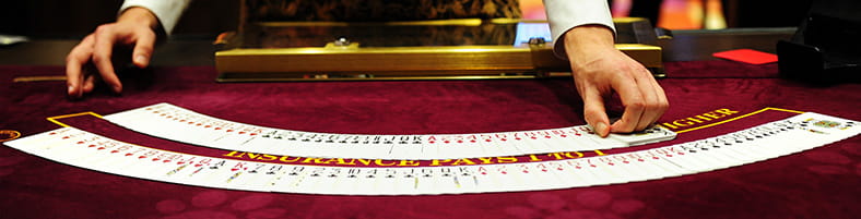 Hands shuffling cards over a table.