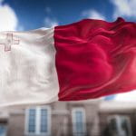 The Waving Flag of Malta On A Blue Background